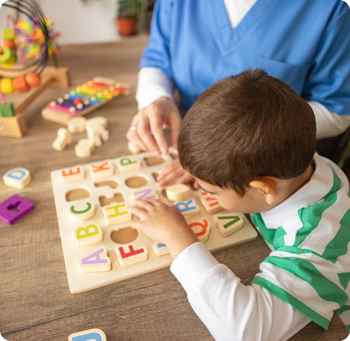 Frame 1618873787 A child and an adult playing with wooden letters.